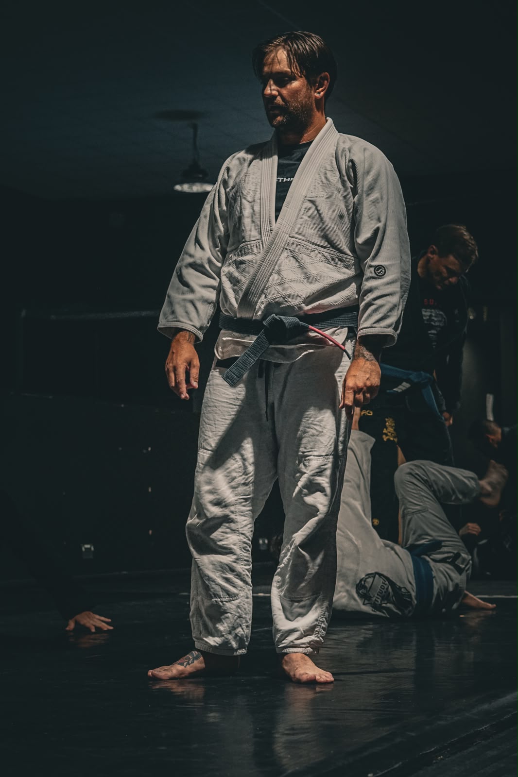 Head Coach Liam Stewart standing on the mats in a white gi